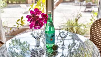 Uma mesa com uma garrafa de água mineral gaseificada S. Pellegrini, dois copos de vinho e um arranjo de flores.