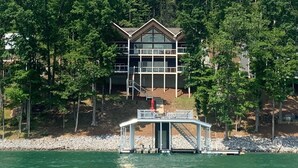 Una cabaña junto al lago con un muelle y un área cubierta para embarcar barcos.