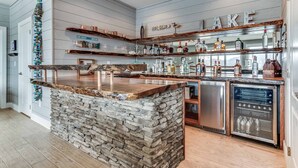Una cocina con una isla de piedra, estanterías de madera y lavavajillas integrado.