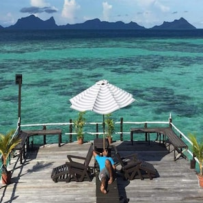 A wooden deck with lounge chairs and an umbrella, overlooking turquoise waters and distant mountains. - Lato Lato Resort (Semporna)