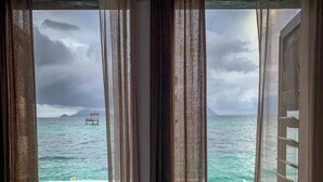 A view from a window with curtains, overlooking turquoise waters and a distant island structure. - Lato Lato Resort (Semporna)
