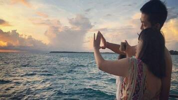Una pareja en un barco con vistas al mar y una isla distante.