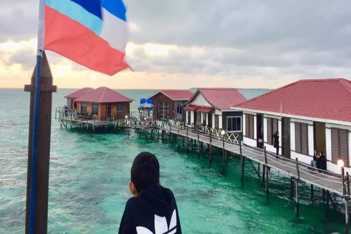 A coastal area with overwater bungalows connected by a wooden walkway.