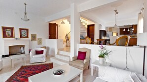 Ein modernes Wohnzimmer mit Kamin, weißen Möbeln und einem roten Teppich mit Muster.