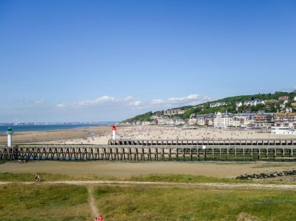 Ein Küstenort mit Strand, Leuchtturm und einer Holzsteganlage.