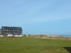 A modern multi-story building with a flat roof, located near a beach.
