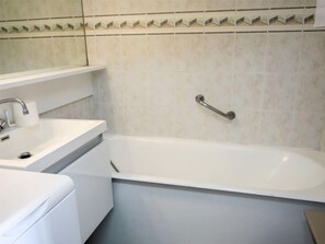 Ein Badezimmer mit einer weißen Badewanne, einem Waschbecken und einem Spiegel.