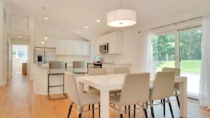 Enjoy meals at the dining table with four chairs, surrounded by a well-equipped kitchen with a central island and large window offering a view of the outdoors.