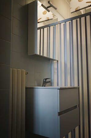 Une salle de bain au design moderne, avec un papier peint à rayures, des toilettes et un meuble de rangement.