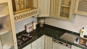 Een keuken met een gasfornuis, een spoelbak en kastjes.