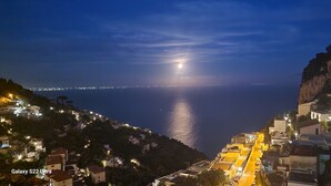 Een kustplaatsje bij nacht met uitzicht op de zee en een maanverlichte hemel.