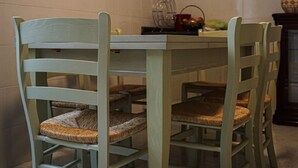 Een eethoek met een tafel, stoelen, een schilderij aan de muur en een betegelde spatwand.