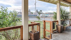 A covered outdoor area with a wooden ceiling, concrete pillars, and a view of a street with houses. There are potted plants and a metal gate. - Dogs friendly, In Town, Walk to Everything (BeachyK) (Long Beach)