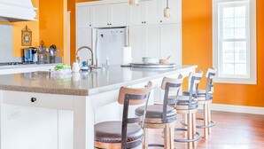 A kitchen with white cabinets, a central island with bar stools, and pendant lighting. - Dogs friendly, In Town, Walk to Everything (BeachyK) (Long Beach)