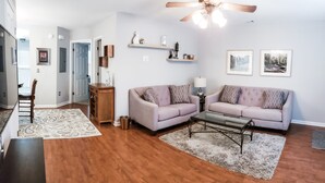 A living room with a wooden floor, two sofas, a coffee table, and a ceiling fan. - College Town Retreat! Close to UGA and Downtown! (Athens)