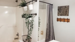 A bathroom with a white sink, a mirror, a shower curtain, and potted plants on the wall. - College Town Retreat! Close to UGA and Downtown! (Athens)