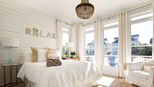 A bedroom with a large bed, a chandelier, a view of the outside, and a sign that says "RELAX". - The Big Dream Getaway 💙Private Heated Pool Sleeps 13 (Atlantic Beach)