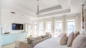 A spacious bedroom with a large bed, a sofa bed, a TV, and a view of the outside. - The Big Dream Getaway 💙Private Heated Pool Sleeps 13 (Atlantic Beach)