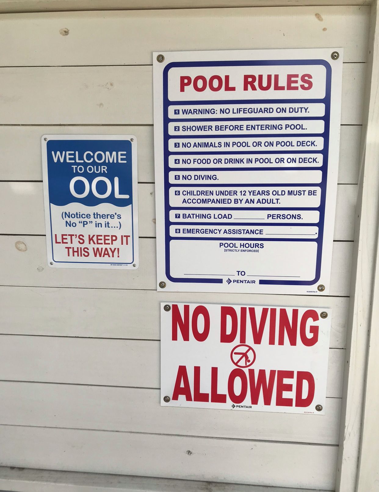 A wall with multiple signs including 'POOL RULES', 'WELCOME TO OUR OOL', and 'NO DIVING ALLOWED'.