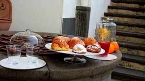 A table with pastries, a glass of juice, and two glasses on a stone surface. - GARDEN OF THE VESUVIUS (Terzigno)