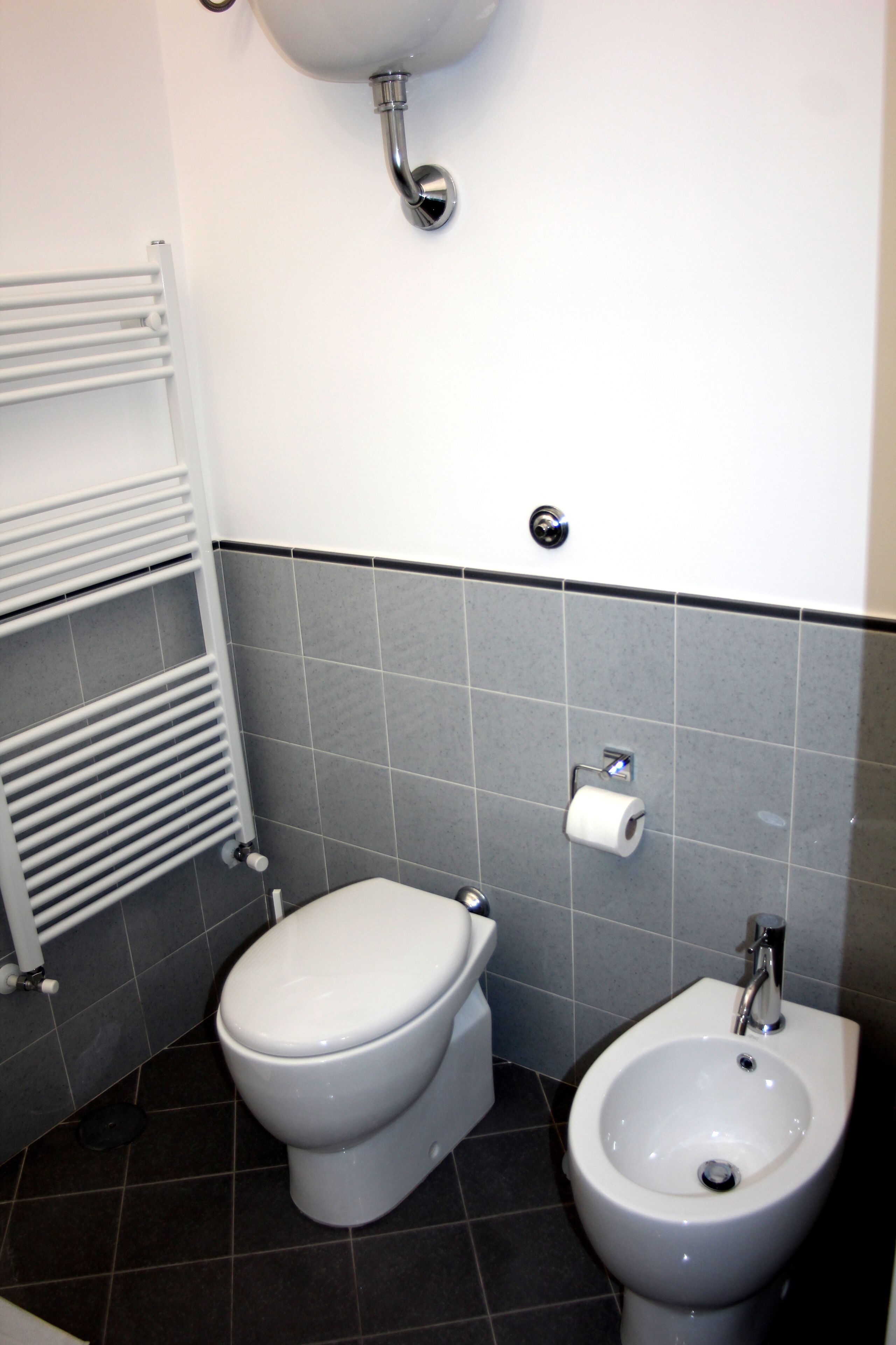Een badkamer met toilet, bidet en een handdoekrek.
