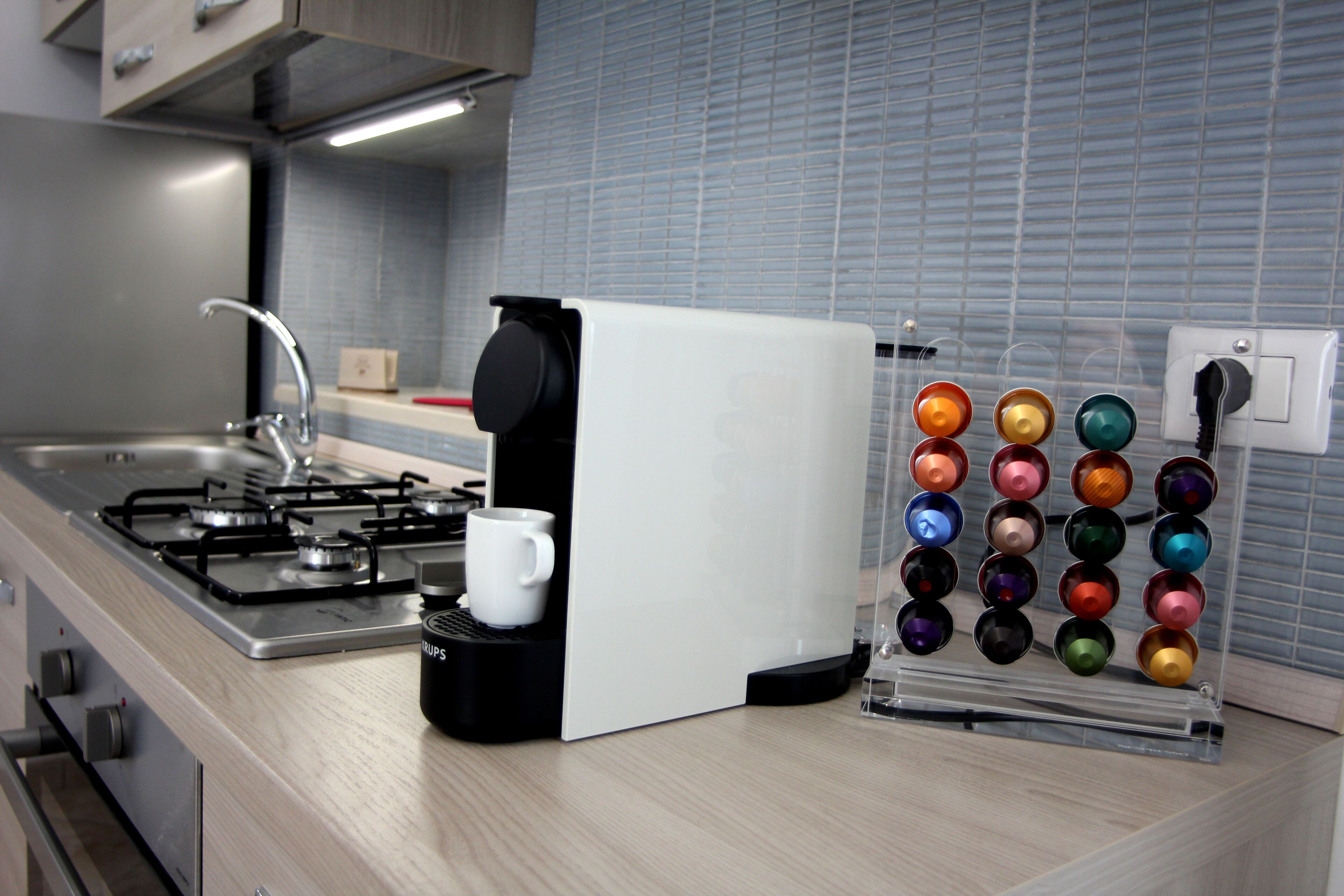 Eine Küche mit Gasherd, Kaffeemaschine und Kaffee-Kapselhalter.