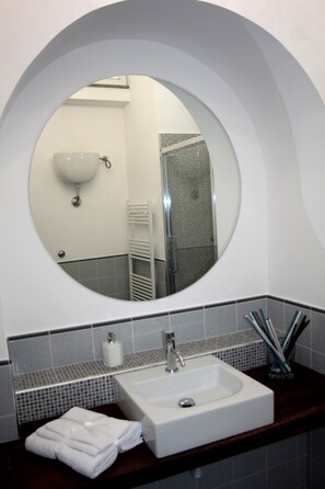 A bathroom with a round mirror, a white sink, and a towel rack. - GARDEN OF THE VESUVIUS (Terzigno)