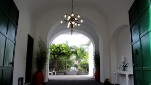 A corridor with a chandelier, potted plants, and a view of a garden through an archway. - GARDEN OF THE VESUVIUS (Terzigno)
