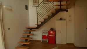 A staircase with wooden steps and metal railings, leading to a landing with a white cabinet and a red appliance. - An oasis of peace: the Honey House (PINEROLO)