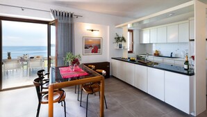 A modern kitchen with white cabinets, a black countertop, and a dining area with a table set for two.