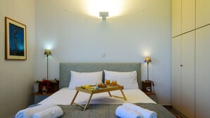 A hotel room with a bed, two bedside lamps, a tray with breakfast items, and towels.
