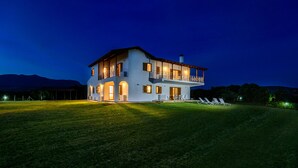 A two-story house with a balcony, a covered patio, and a well-lit lawn area.
