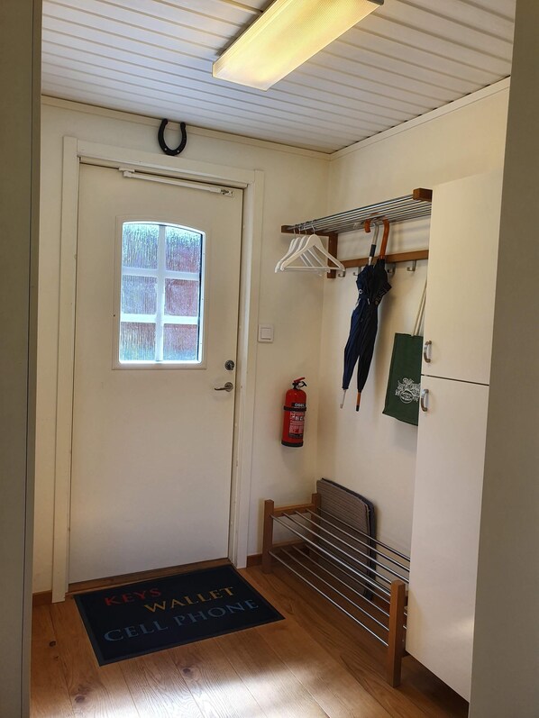 A hotel entrance with a door, a window, a fire extinguisher, a coat rack, and a bench.