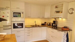 A modern kitchen with white cabinets, a microwave, an oven, a sink, and a coffee maker.
