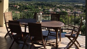 Un espace extérieur aménagé, abrité et doté de tables et de chaises, offrant une vue panoramique sur la ville et les collines environnantes.