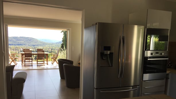 Une cuisine moderne équipée d’un réfrigérateur et d’un four en acier inoxydable, ainsi que d’un coin repas avec une table et des chaises.