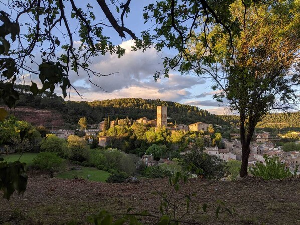 A historic village with stone buildings, a prominent tower, and lush greenery.