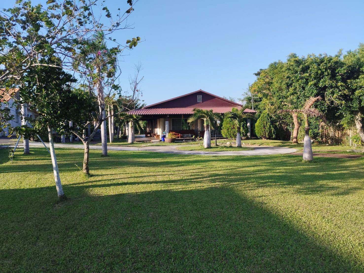 A building with a red roof, surrounded by a well-maintained lawn and trees.