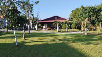 A building with a red roof, surrounded by a well-maintained lawn and trees.