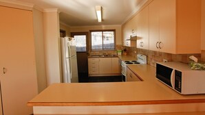 A compact kitchen with a refrigerator, stove, microwave, and sink.