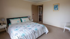 A bedroom with a bed, nightstands, a chair, a door, and a painting on the wall.