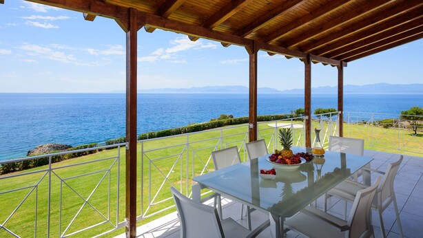 Un espace extérieur abrité, aménagé pour les repas, avec une table pour deux, offrant une vue sur un paysage côtier.
