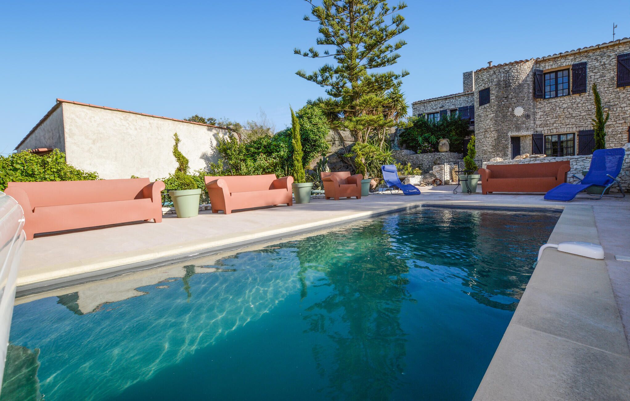 Una piscina amb gandules i un edifici de pedra al fons.