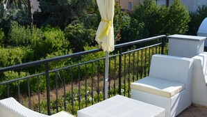 Ein Balkon mit weißen Korbmöbeln, darunter zwei Sofas und ein kleiner Tisch, sowie ein gelber Sonnenschirm.