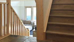 Una escalera con barandillas de madera y piso de losas de piedra que conduce a una sala de estar con sofá y una mesa de centro.