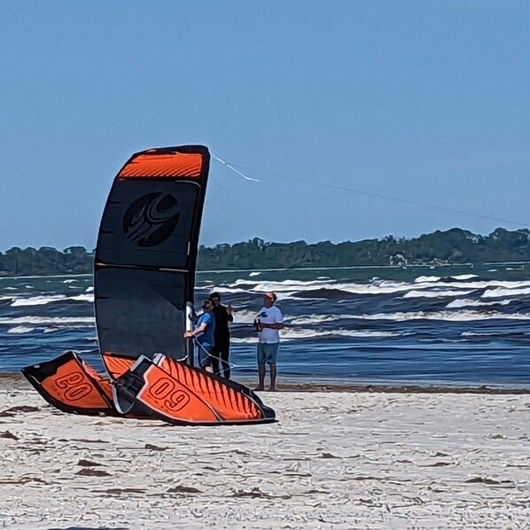 A beach with a windsurfing board and two people standing by the water. - Reusenhaus South in Breege (Breege)
