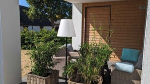 A covered outdoor seating area with wicker furniture and potted plants. - Reusenhaus South in Breege (Breege)
