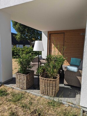 A covered outdoor seating area with wicker furniture and potted plants. - Reusenhaus South in Breege (Breege)