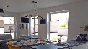 A modern kitchen with a central island, large windows, and a dining area with a sofa and chairs. - Reusenhaus South in Breege (Breege)