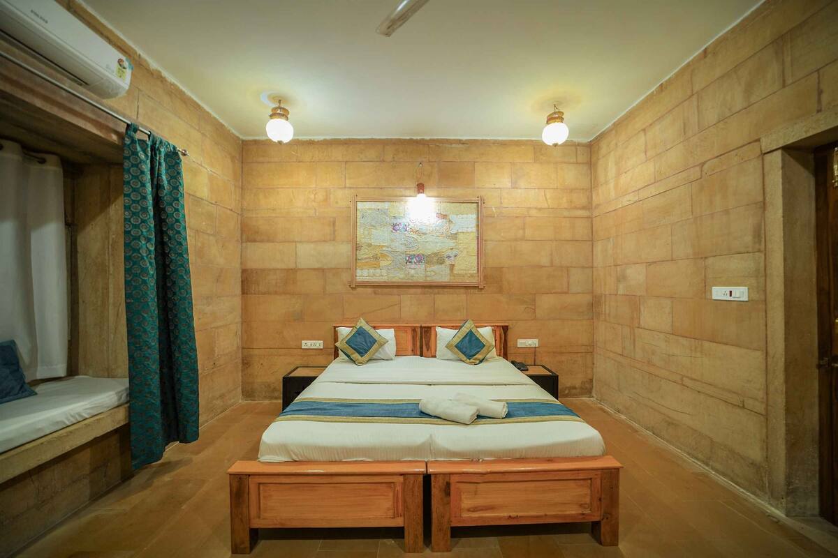 A bedroom with a wooden bed, two bedside tables, a nightstand, a wall-mounted air conditioner, and a ceiling light fixture.